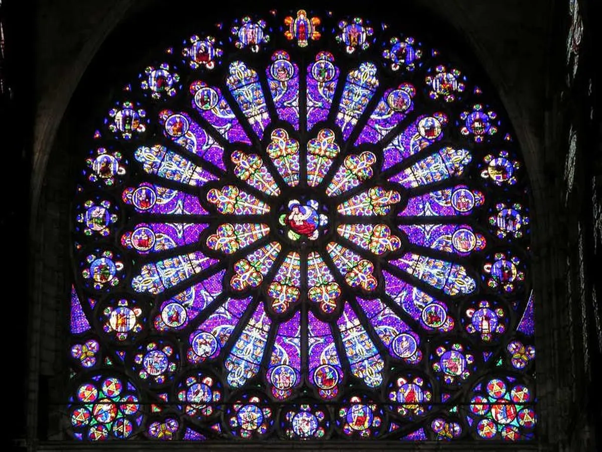 Vitrail circulaire aux motifs complexes et aux couleurs vives, principalement violettes, représentant divers personnages et scènes.