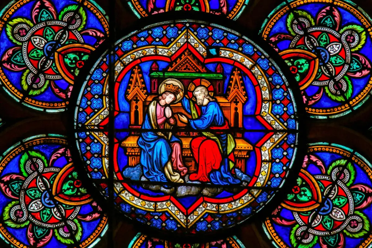 Vitrail représentant deux personnages auréolés, vêtus de robes bleues et rouges, assis sur un trône au fond coloré et orné.