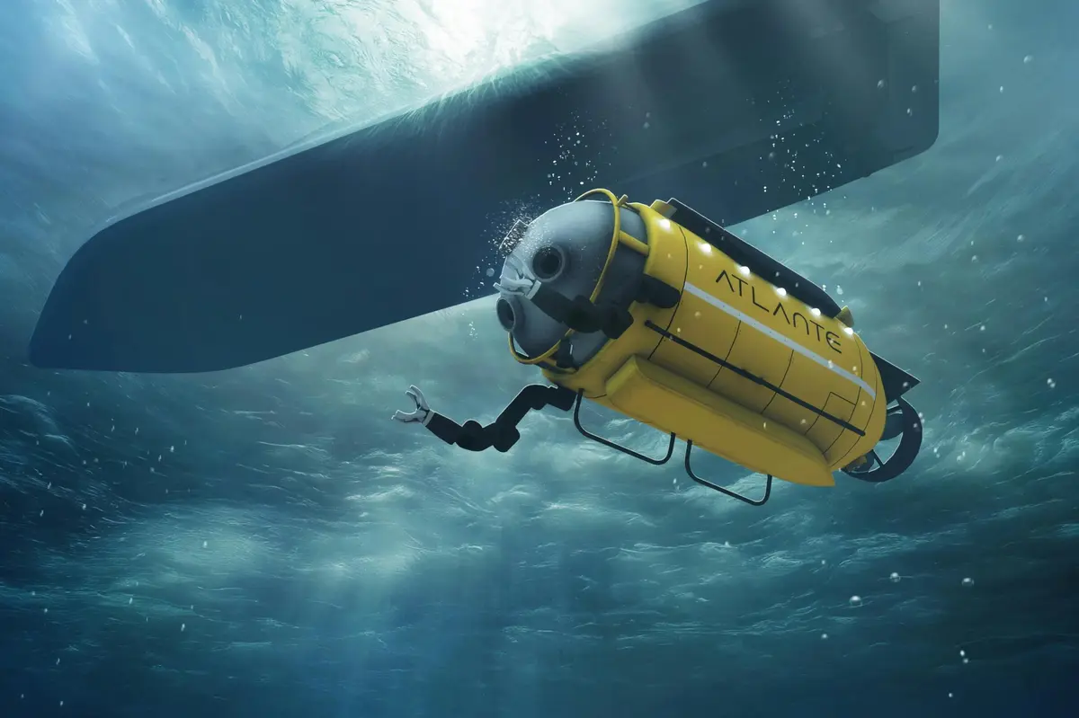 Un véhicule sous-marin jaune étiqueté ATLANTE explorant sous une structure immergée dans l'eau bleue de l'océan.