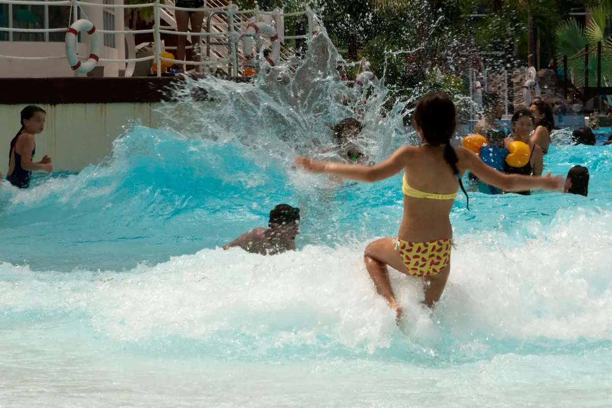 Enfants jouant et s'éclaboussant dans une piscine à vagues par une journée ensoleillée.