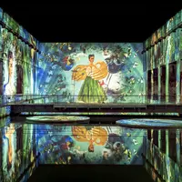 Une grande exposition intérieure avec des projections murales vibrantes présentant des œuvres d'art, dont une figure en vert, se reflétant sur l'eau en contrebas. &copy; @Culturespaces / Geoffroy Groult