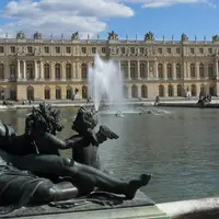 Statues devant une grande fontaine et le château de Versailles sous un ciel partiellement nuageux. &copy; G CHP