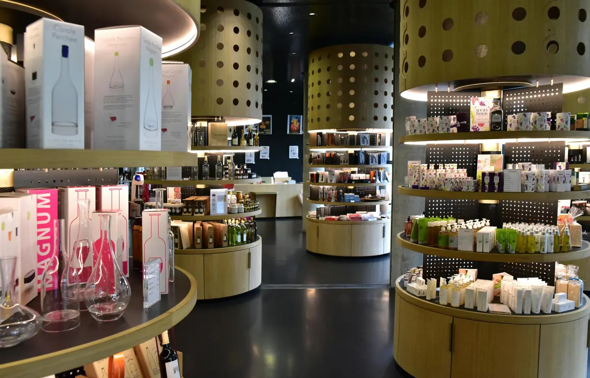 Un intérieur de magasin moderne avec des étagères en bois incurvées et des présentoirs cylindriques, mettant en valeur divers flacons, boîtes et produits.