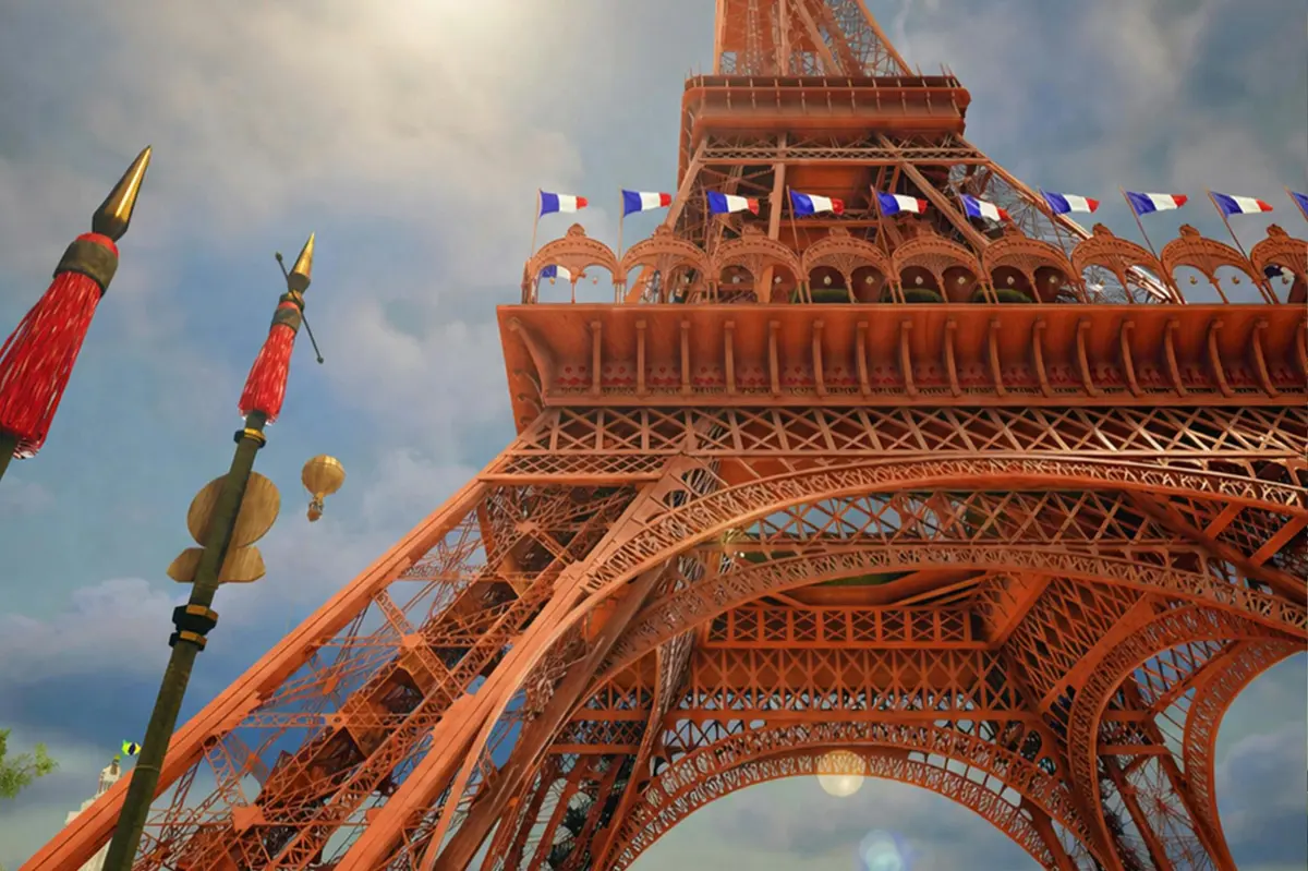 Vue en contre-plongée de la Tour Eiffel, avec des drapeaux français et un mât décoratif se détachant sur un ciel partiellement nuageux.