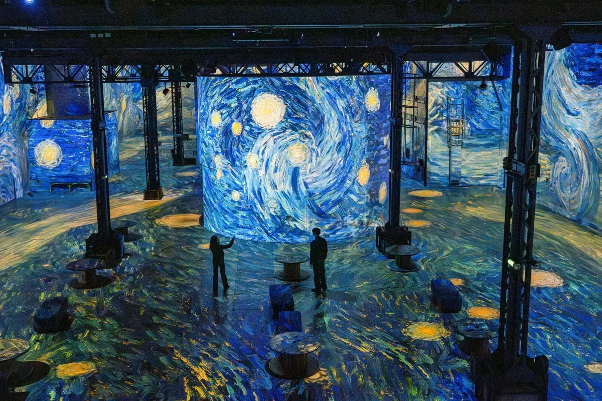 Une installation d'art numérique mettant en scène « La Nuit étoilée » de Van Gogh, où les visiteurs peuvent admirer des projections sur les murs et au sol.