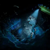 Scène sous-marine avec trois plongeurs explorant une structure engloutie éclairée par le projecteur d'un sous-marin. &copy; TITANIC