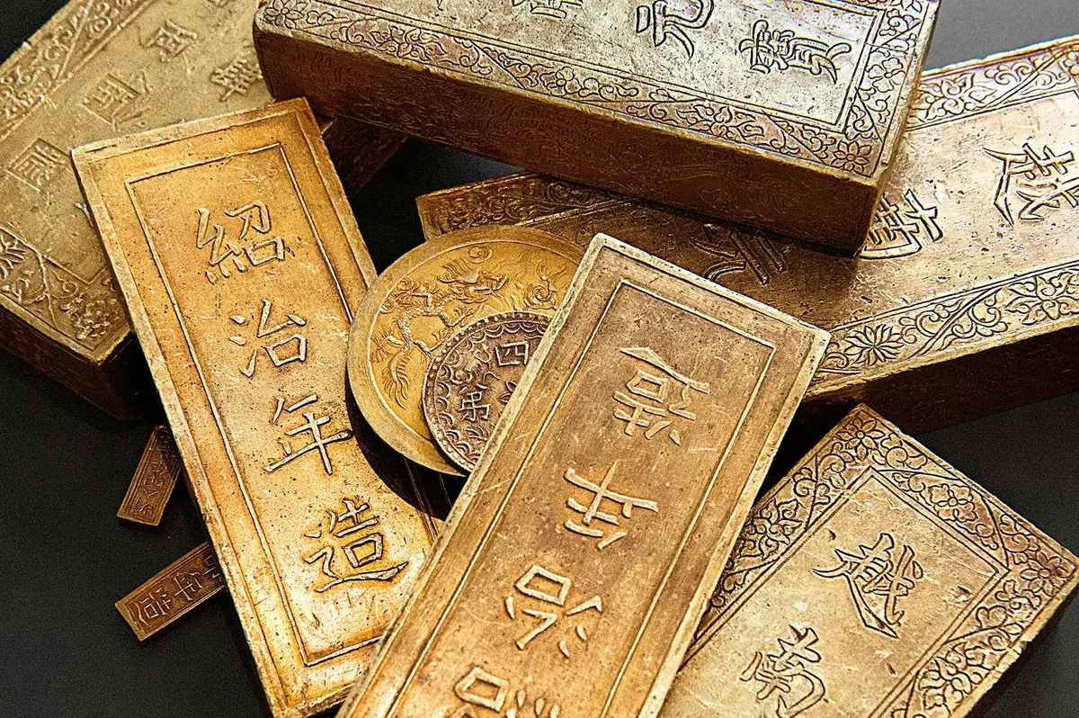 Barres et pièces d'or avec des gravures complexes et des caractères chinois.