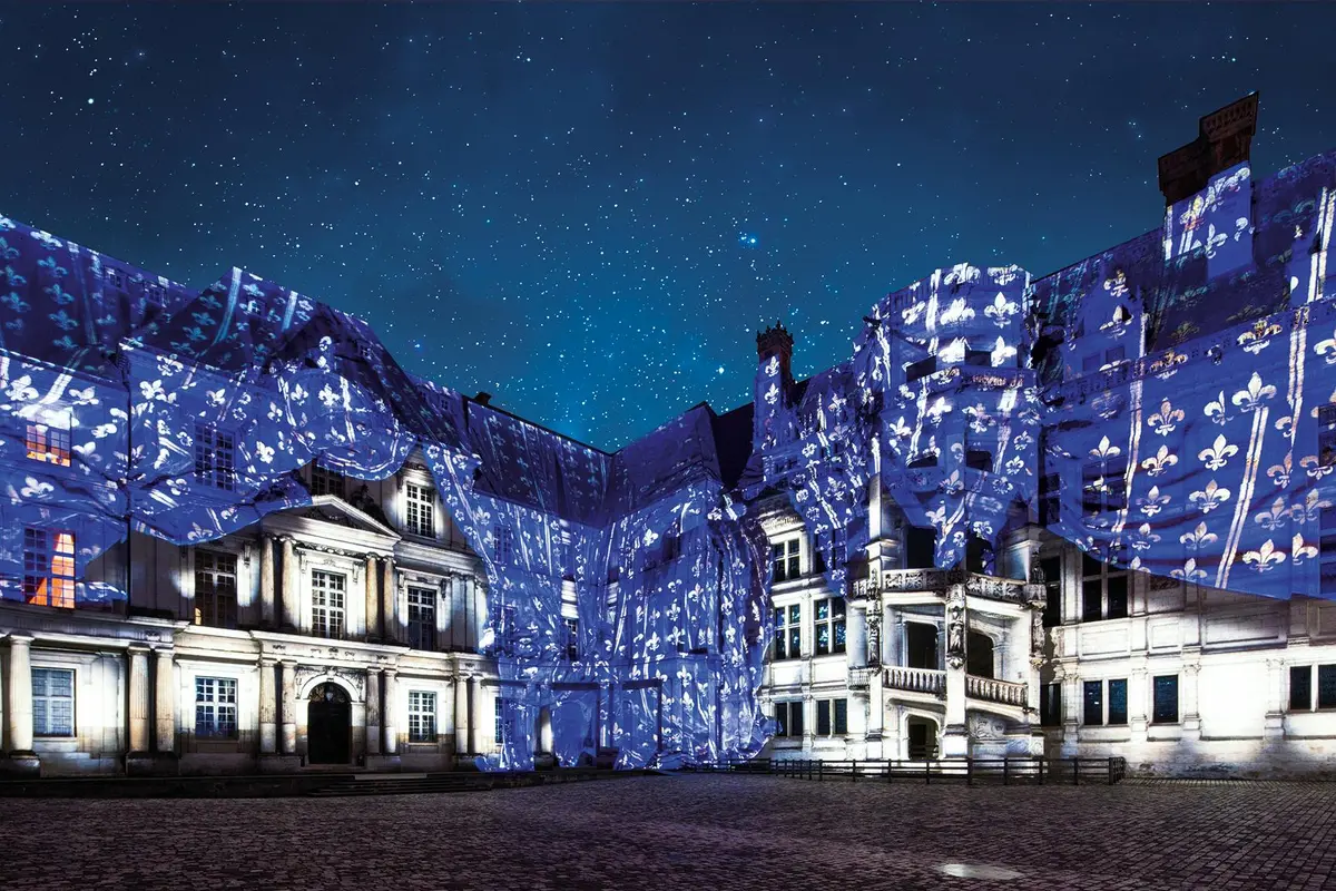 Un bâtiment historique illuminé par des projections lumineuses sous un ciel étoilé.