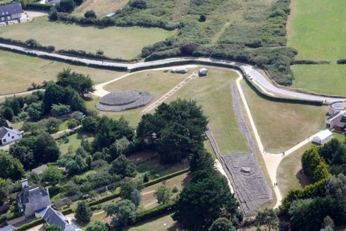 Vue aérienne d'un paysage herbeux avec d'anciens monticules de pierre, des chemins et des arbres.
