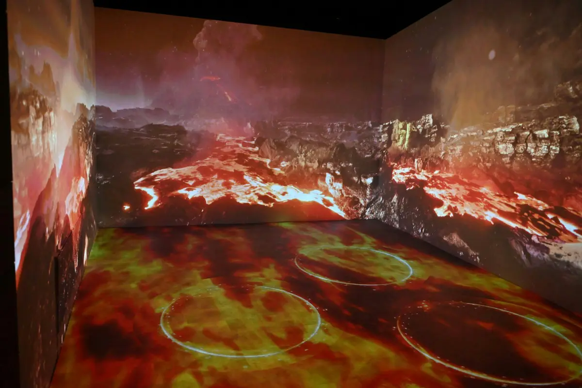 Une pièce dont les murs et le sol affichent une projection d'un paysage volcanique enflammé avec de la lave et de la fumée.
