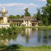 Un château au bord d'un lac avec une tour, des arches en bois, une végétation luxuriante et une surface d'eau réfléchissante sous un ciel partiellement nuageux. &copy; Daderot