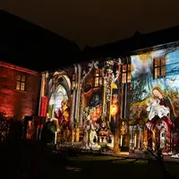 La façade d'un immeuble, éclairée la nuit par des projections artistiques colorées représentant des motifs et des personnages religieux. &copy; Musée Unterlinden