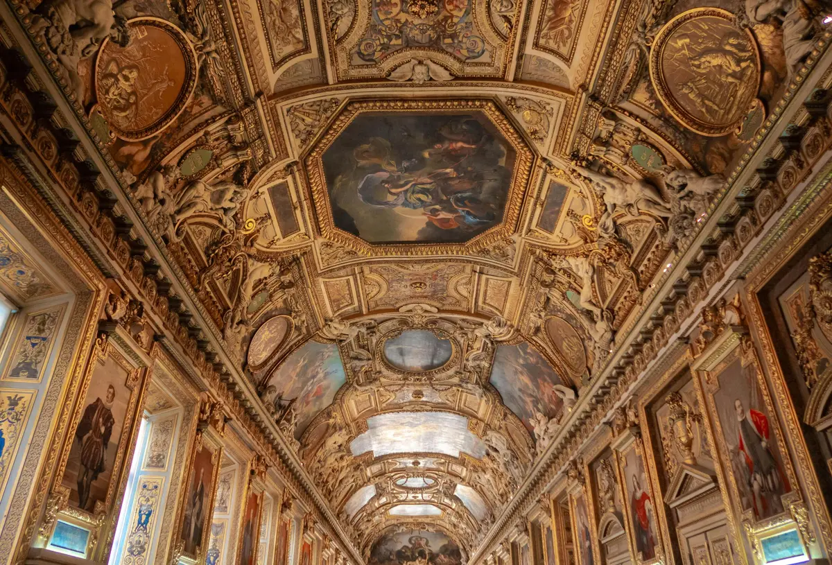 Plafond orné de peintures et de sculptures complexes dans un espace intérieur architectural grandiose.
