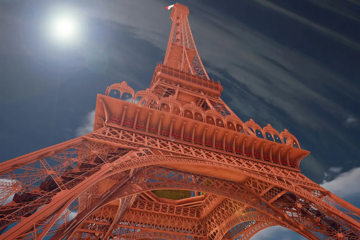 Vue vers le haut de la Tour Eiffel sous un ciel ensoleillé, avec des effets de flare et un petit drapeau français au sommet.
