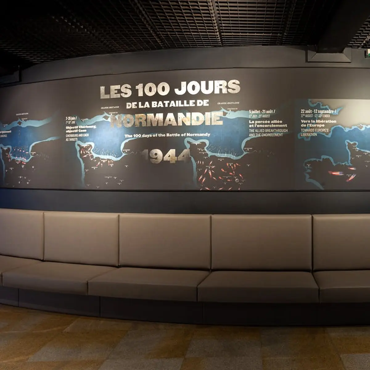Panneau d'affichage Les 100 Jours de la Bataille de Normandie avec une chronologie et une carte. Sièges gris incurvés à l'avant.