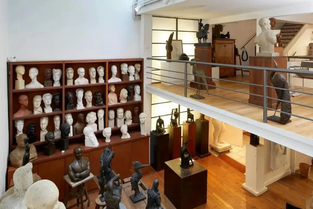 Une salle d'exposition présentant de nombreuses sculptures en buste sur des étagères et diverses statues placées sur des piédestaux.