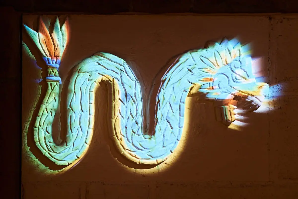 Art mural décoratif représentant un serpent à plumes coloré, aux motifs complexes et aux teintes bleues, jaunes et orange éclatantes.