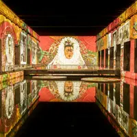 Une peinture murale vibrante dans un hall avec une surface d'eau réfléchissante, avec un portrait proéminent d'une femme en tenue traditionnelle. &copy; @Culturespaces / Geoffroy Groult