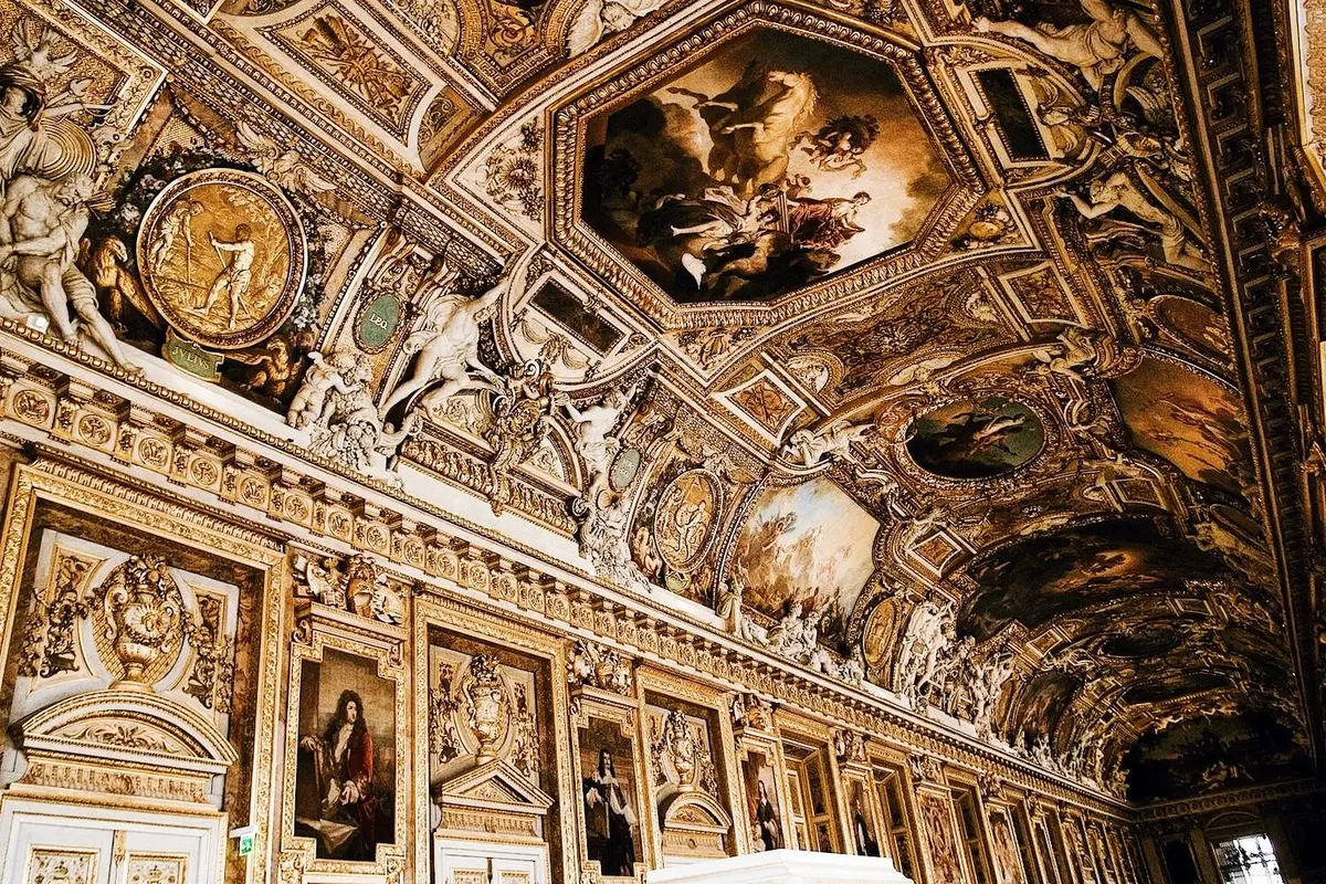 Une salle ornée, dorée, avec des peintures détaillées, des sculptures et des motifs complexes couvrant le plafond et les murs.