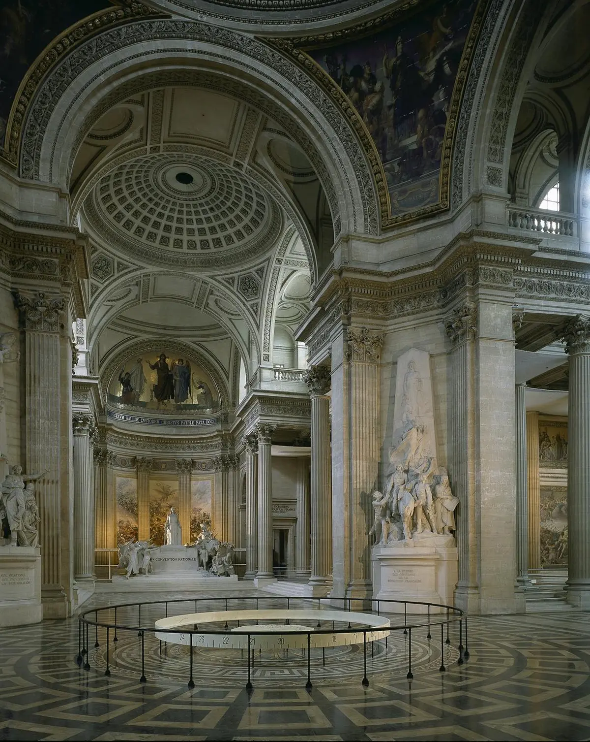 Intérieur grandiose d'un bâtiment néoclassique avec de hautes colonnes, des statues, un plafond en dôme complexe et de grandes peintures murales.