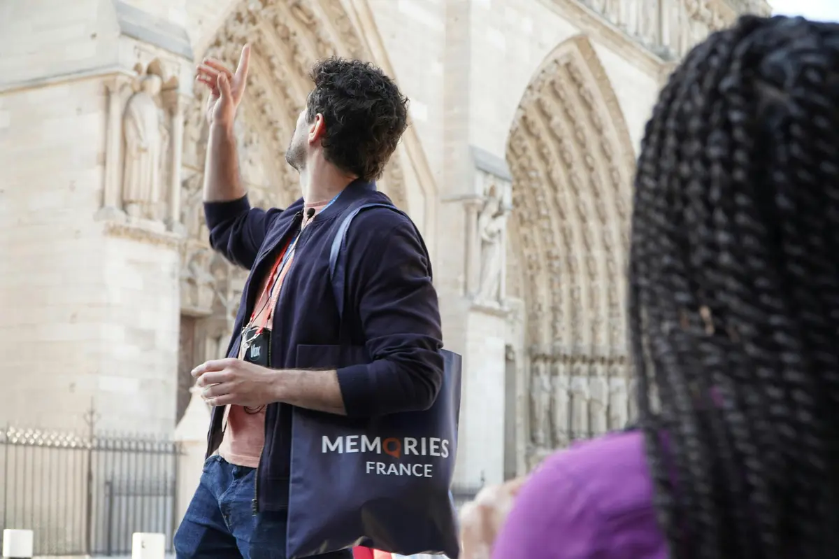 Guide pointing out details on the facade of Notre Dame Cathedral