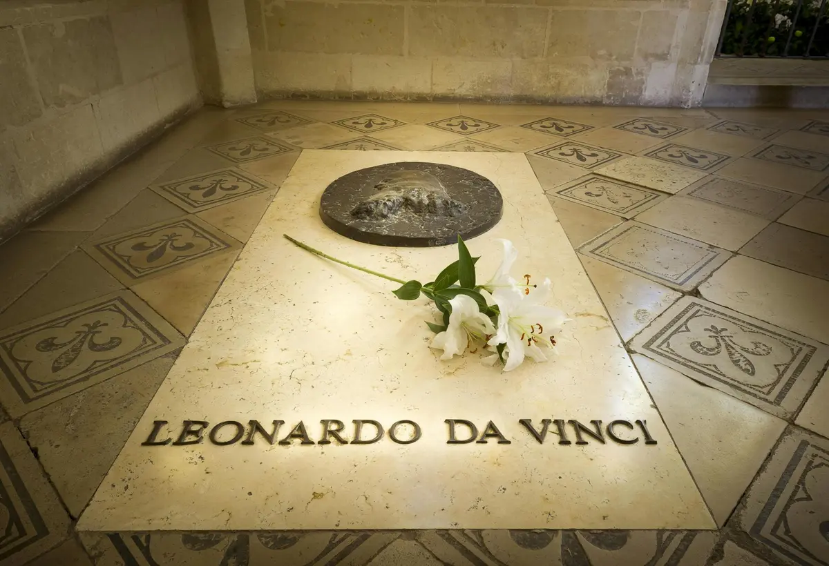 Une fleur posée sur une dalle de pierre portant l'inscription Leonardo da Vinci sur un sol carrelé.