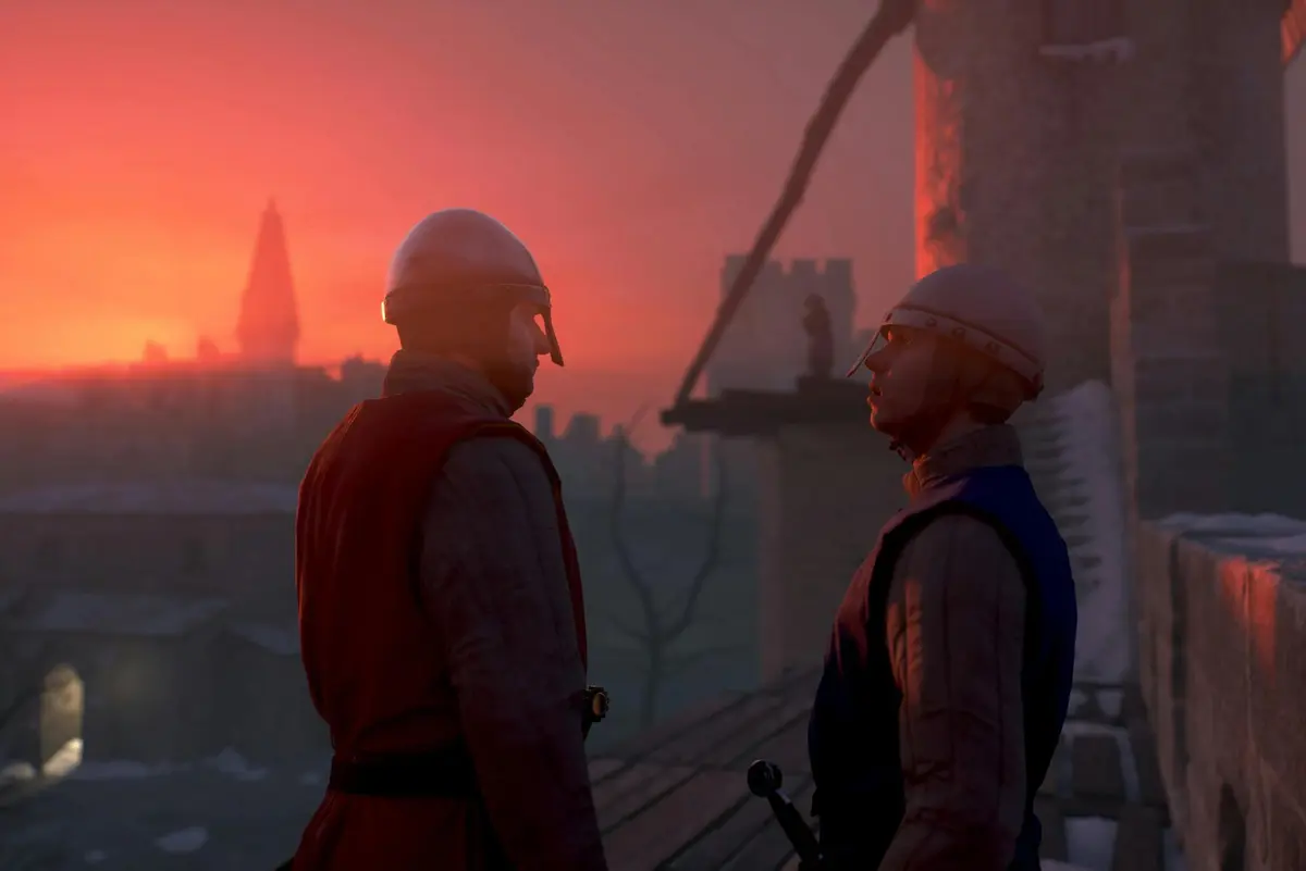 Deux soldats médiévaux en armure se tiennent sur un toit au coucher du soleil, avec en arrière-plan une silhouette lointaine sur une tour et la ligne d'horizon d'une ville.