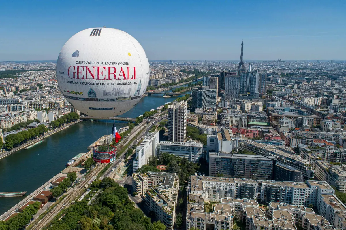 Vue aérienne de Paris avec en arrière-plan une grande montgolfière Generali, le drapeau français et la Tour Eiffel.