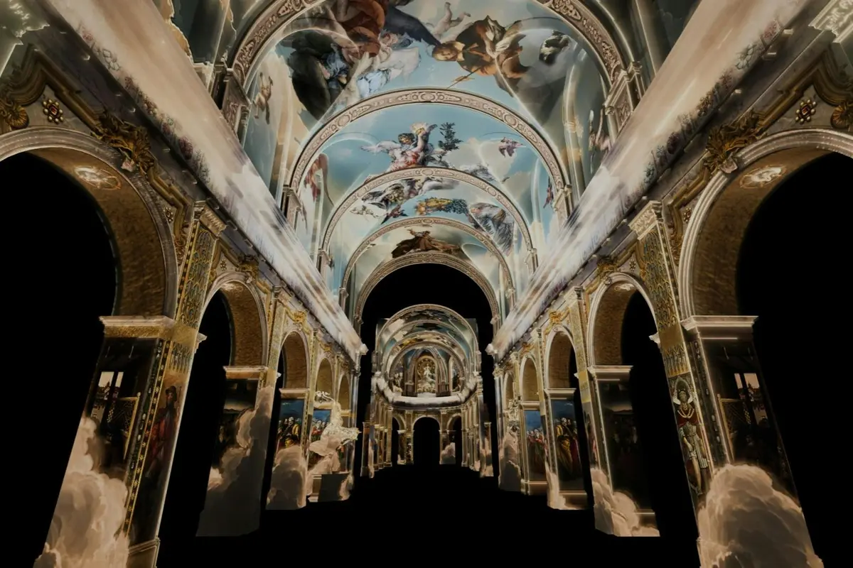Une grande salle aux plafonds richement peints, représentant des scènes d'anges et de personnages, entourée d'arcades et d'éléments architecturaux minutieusement travaillés.