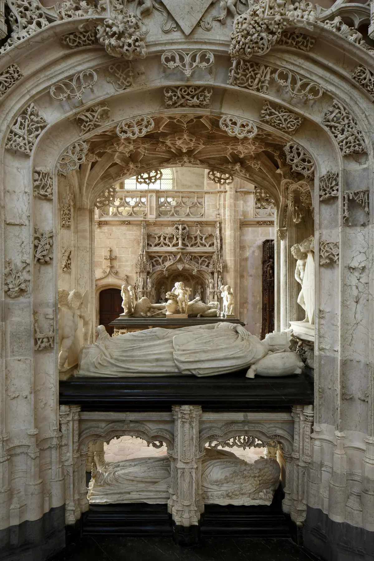 Des tombes en pierre ornées de sculptures et de statues détaillées à l'intérieur d'une cathédrale de style gothique.