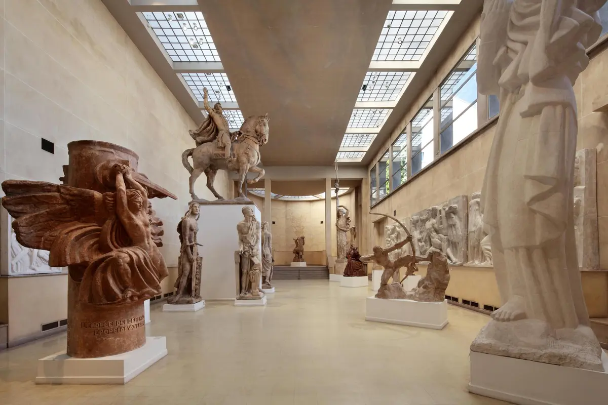 Une salle de musée présente diverses grandes sculptures classiques, notamment des statues de cavaliers, de guerriers et de figures mythologiques.