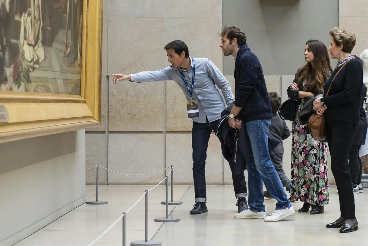 Deux hommes examinent attentivement un grand tableau encadré dans un musée, l'un pointant du doigt et l'autre se penchant vers l'avant.