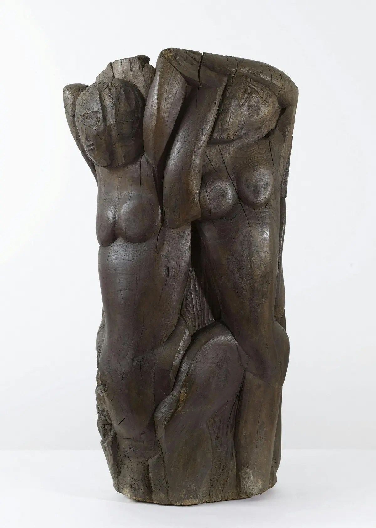 Sculpture en bois sculpté représentant deux figures humaines abstraites dont le torse et la tête sont visibles sur un fond uni.