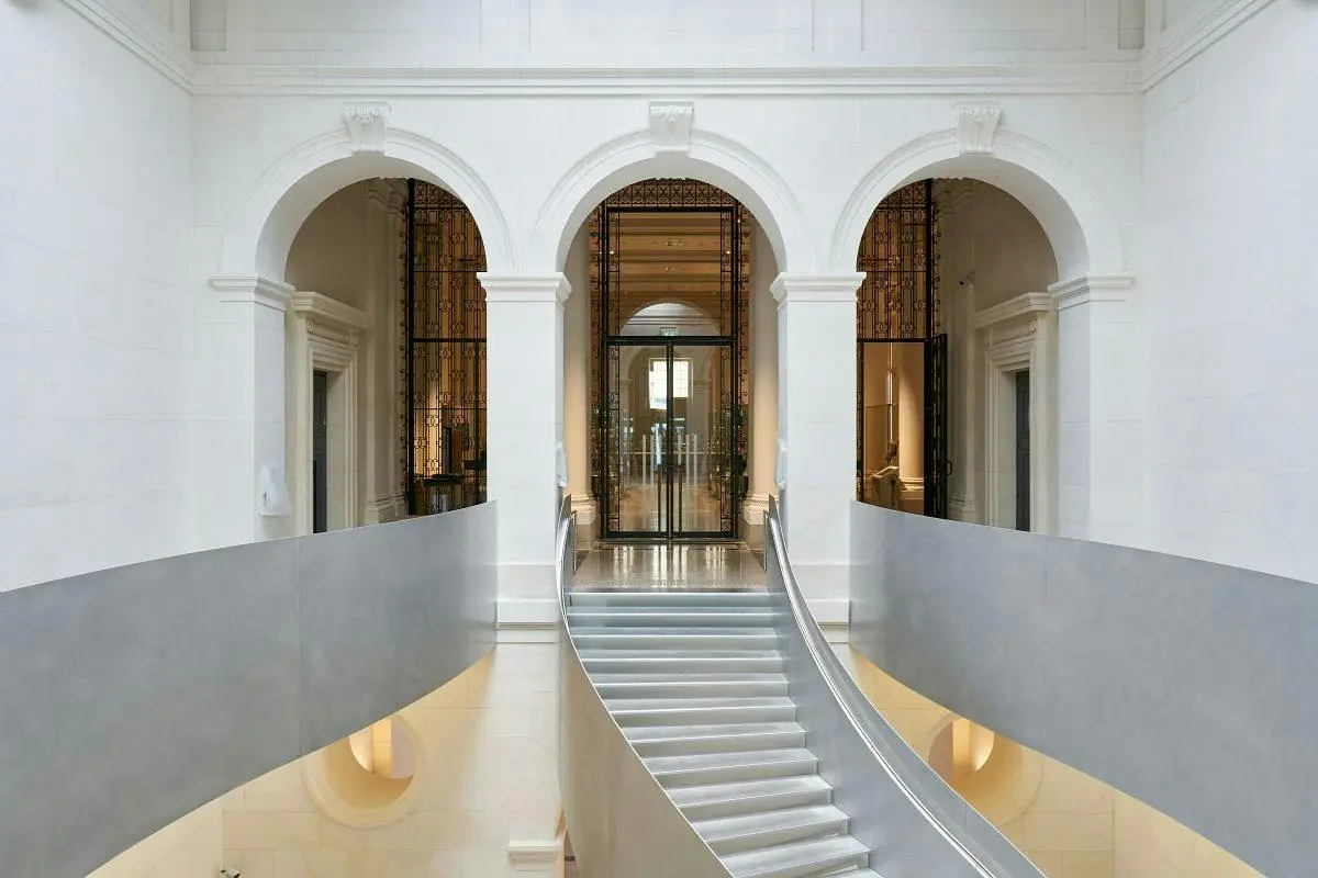 Un intérieur somptueux, avec des portes cintrées, un escalier doté de rampes métalliques et de hauts plafonds au style classique.