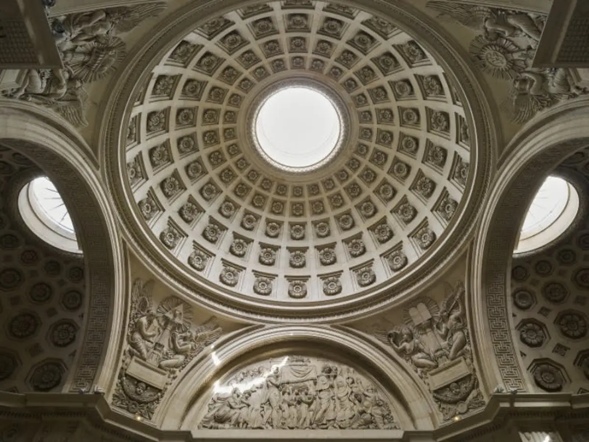 Plafond à coupole ornée d'un oculus central, de sculptures complexes et de reliefs détaillés représentant divers personnages de style classique.