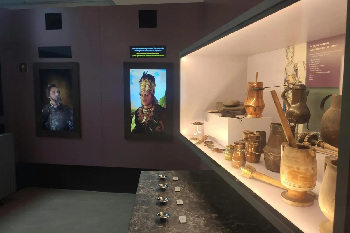 Une exposition de musée présentant des portraits historiques et une collection d'objets anciens dans une vitrine bien éclairée.