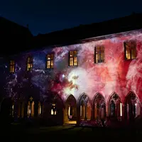 Un bâtiment aux fenêtres cintrées, illuminé la nuit par une projection cosmique aux couleurs éclatantes. &copy; Musée Unterlinden
