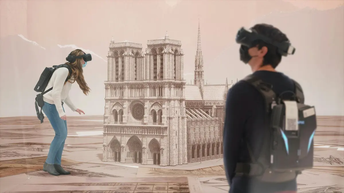 Deux personnes portant des casques de réalité virtuelle interagissent avec un modèle numérique de la cathédrale Notre-Dame dans une pièce.