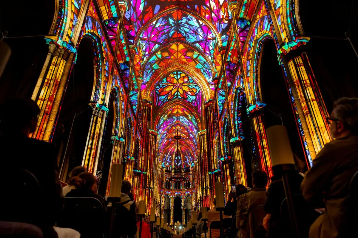 Intérieur somptueux d'une cathédrale, avec ses vitraux aux couleurs vives et éclatantes et son plafond voûté, vu depuis l'allée latérale.