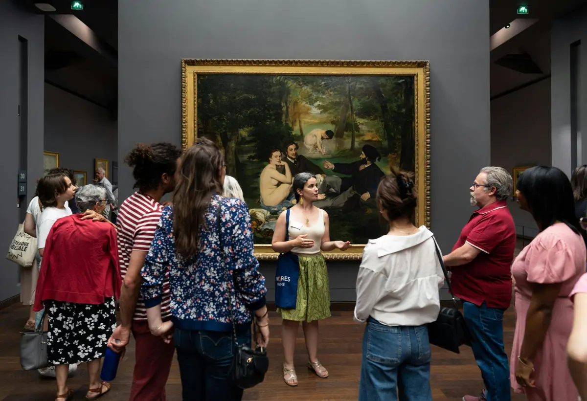Guide and small group in front of the painting Déjeuner Sur l'Herbe by Manet