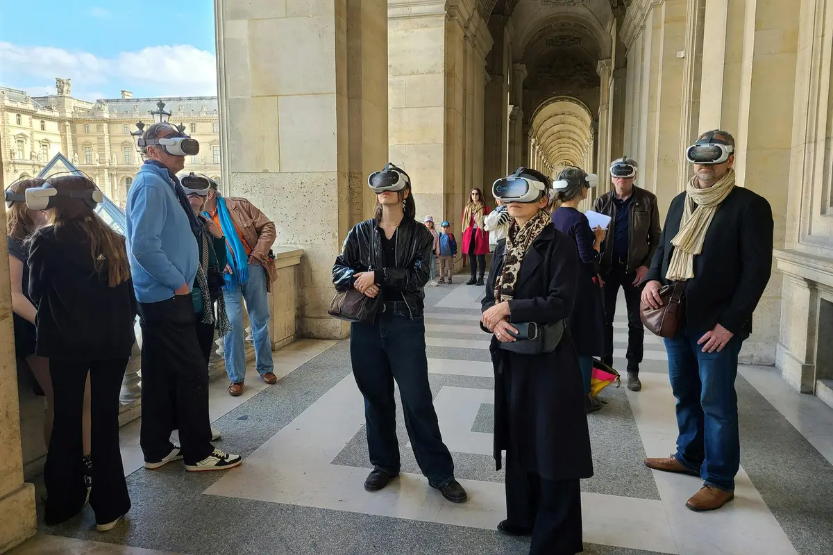 Un groupe de personnes portant des casques de réalité virtuelle se tient dans un couloir d'un bâtiment historique.