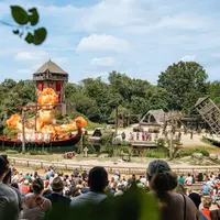 Spectacle en plein air avec un bateau, des flammes, des structures en bois et une foule qui assiste à un spectacle sur le thème du Moyen-Âge. DR