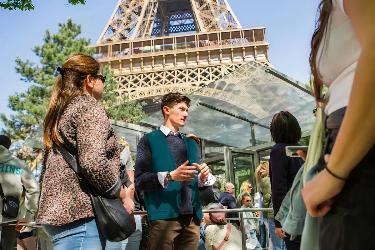 Un groupe de personnes s'était rassemblé au pied de la Tour Eiffel ; l'une d'entre elles semblait donner des indications ou fournir des explications.