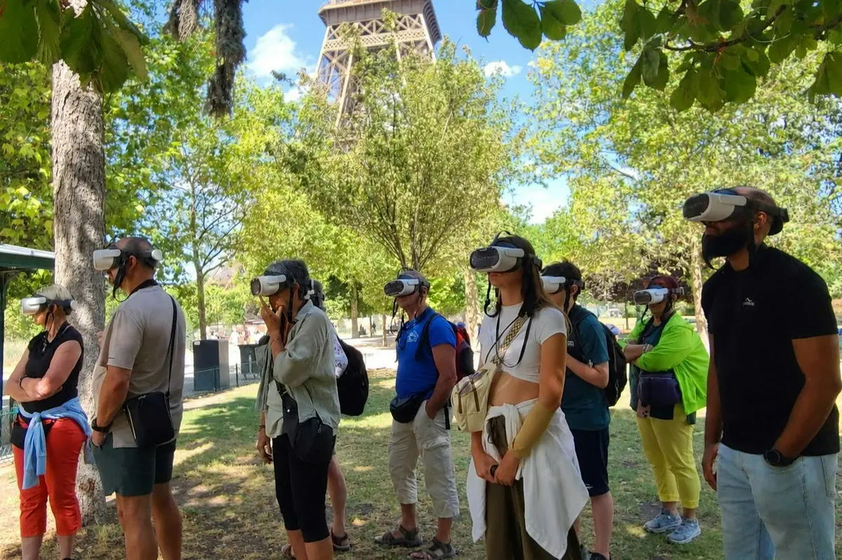 Un groupe de personnes portant des casques de réalité virtuelle dans un parc, avec la Tour Eiffel en arrière-plan.