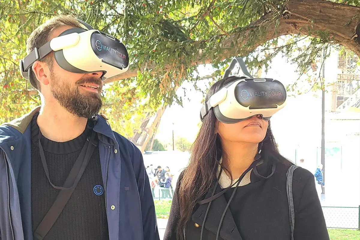 Deux personnes en extérieur portant des casques de réalité virtuelle avec des arbres en arrière-plan.