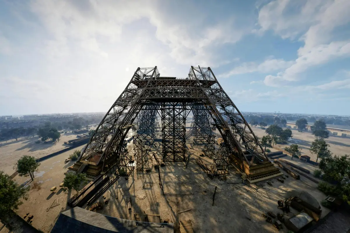 Une grande structure métallique en cours de construction dans un espace ouvert, sous un ciel dégagé, avec de la végétation clairsemée tout autour.