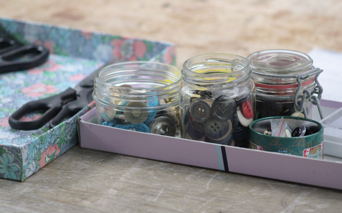 Photographie de boîtes contenant des boutons et des ciseaux, prise lors d’un atelier de couture à la main.Photographie de boîtes contenant des boutons et des ciseaux, prise lors d’un atelier de couture à la main.