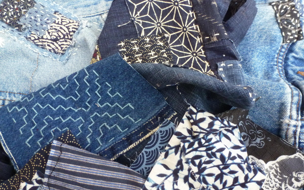 Photographie de plusieurs morceaux de tissus dont du jeans, sur lesquels ont été brodés des motifs ou des pièces en utilisant les techniques du Boro et du Sashiko.