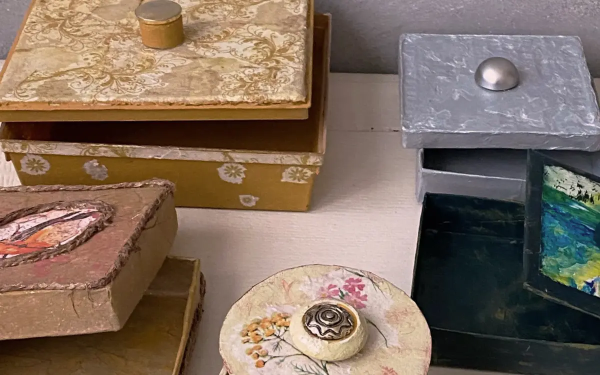 Photographie de quatre boîtes qui ont été customisées et upcyclées avec des papiers de couleur, de la peinture etc. Créations qui ont été réalisées lors de l'atelier décoration de boîtes.
