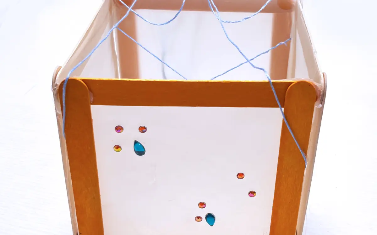 Photographie d'une lanterne de la forêt orange créée à partir de papier calque, de bâtonnets et de strass.